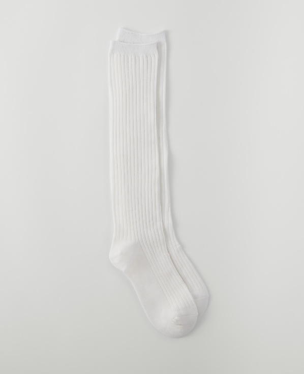 A pair of white ribbed knee-high socks lies on a plain white background.