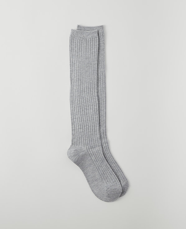 A pair of ribbed grey knee-high socks lies on a plain light grey background.