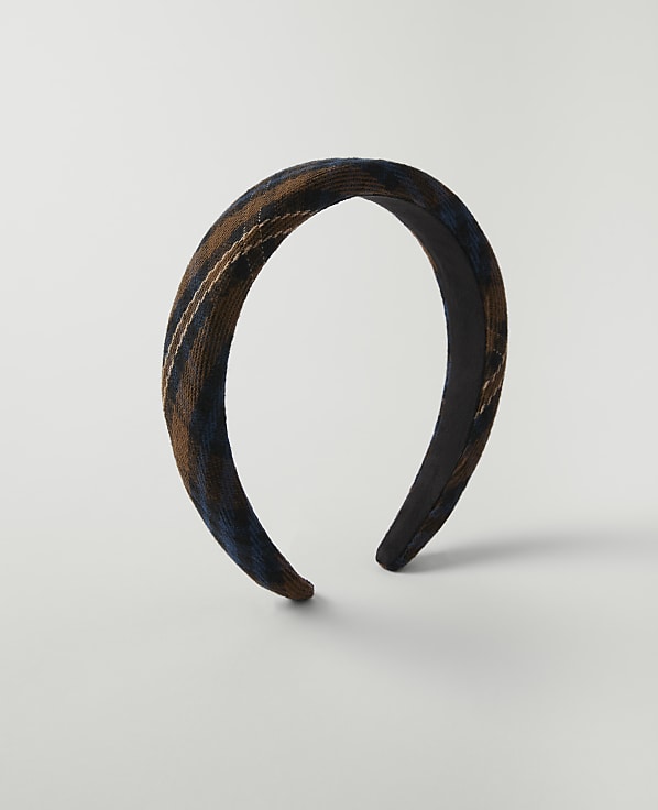 A brown and blue plaid headband rests on a plain white background.