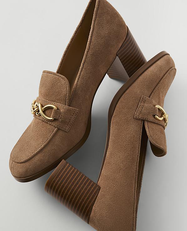 A pair of brown suede loafers with gold chain accents and chunky heels rests on a plain white background.