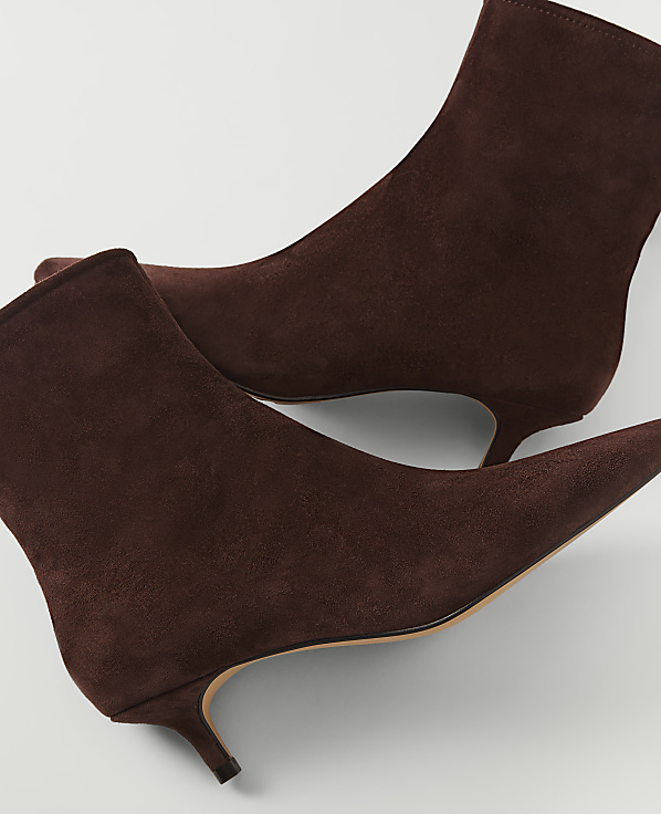 A pair of brown suede kitten heel ankle boots are displayed against a plain white background.