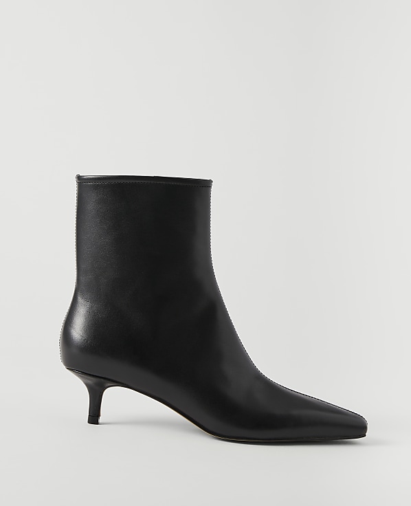 A sleek black leather ankle boot with a pointed toe and kitten heel stands against a plain white background.