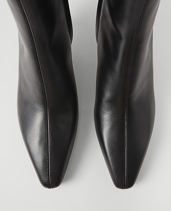 A pair of sleek black leather boots with pointed toes are presented against a plain white background.