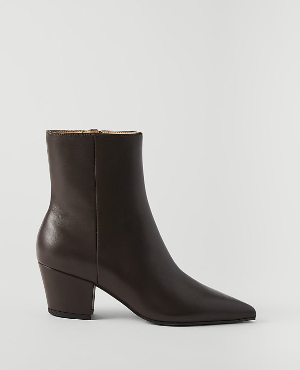 A brown leather ankle boot with a pointed toe and block heel stands on a white surface against a plain white background.