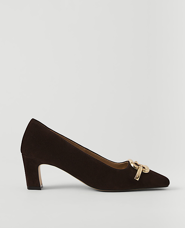 A dark brown suede pump with a gold buckle detail rests on a plain white background.