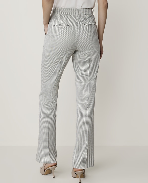 A person wearing checkered pants and heels stands against a plain white background.