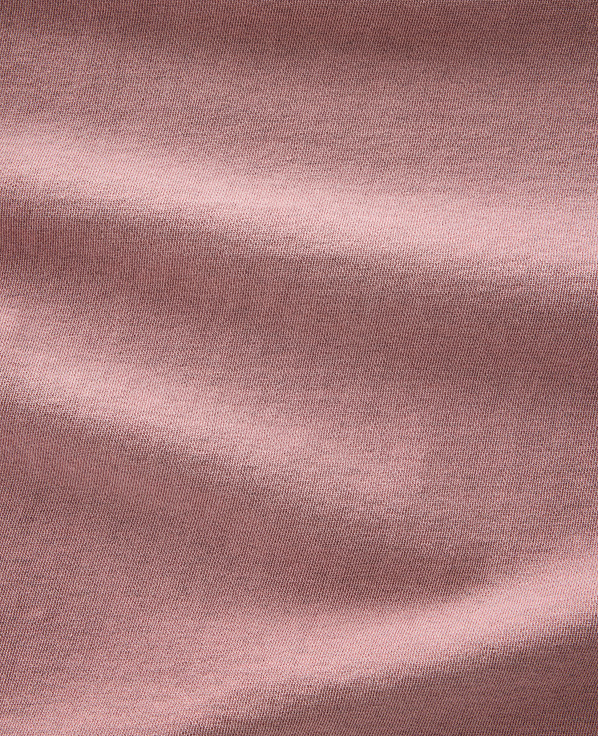 Soft, dusty rose fabric folds and creases across the frame, with subtle texture visible throughout.