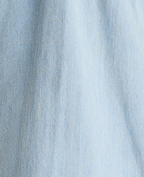 A close-up of light blue denim fabric fills the frame, with subtle vertical lines and a soft, textured weave visible throughout.