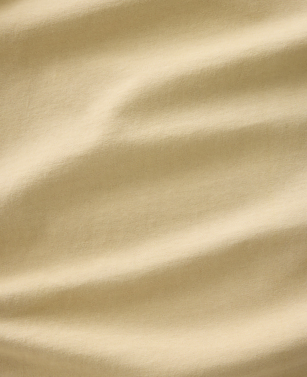 Soft, rippling folds of a light tan fabric fill the frame, creating a textured and abstract background.