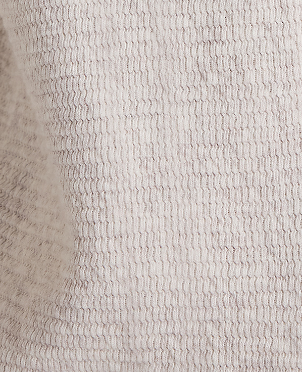 A close-up view of a textured, light gray fabric fills the frame, with subtle variations in shade creating a soft, mottled background.