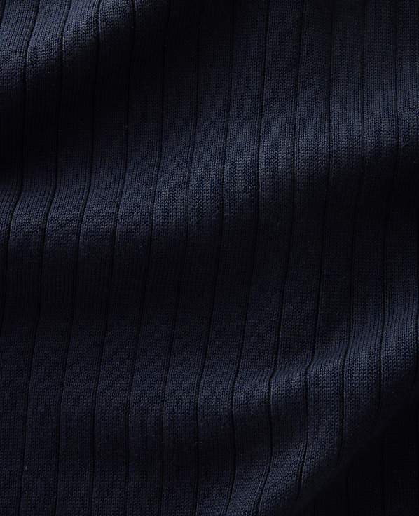 A close-up view of dark navy ribbed fabric fills the frame, with subtle shadows highlighting the vertical texture.