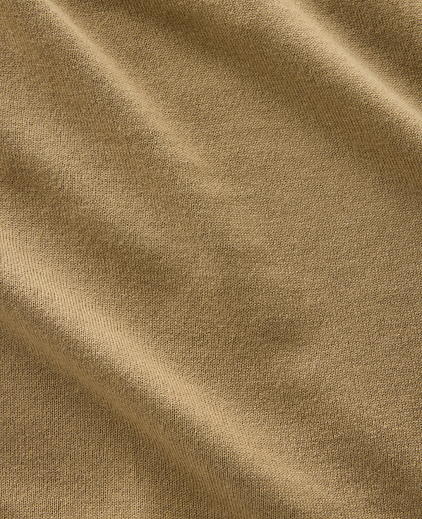 A close-up view of a tan fabric with soft folds and a textured weave fills the frame.