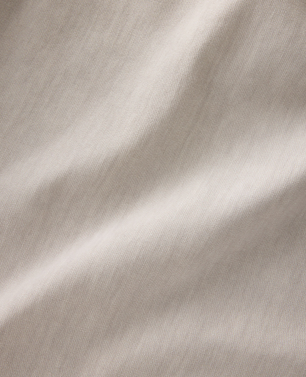 Soft, flowing folds of light brown fabric are illuminated by gentle light, creating subtle shadows and highlights across the textured surface.