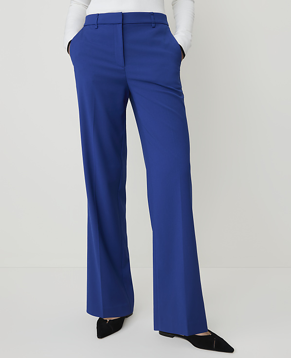 A person stands in bright blue flared trousers and black pointed shoes against a plain white background.