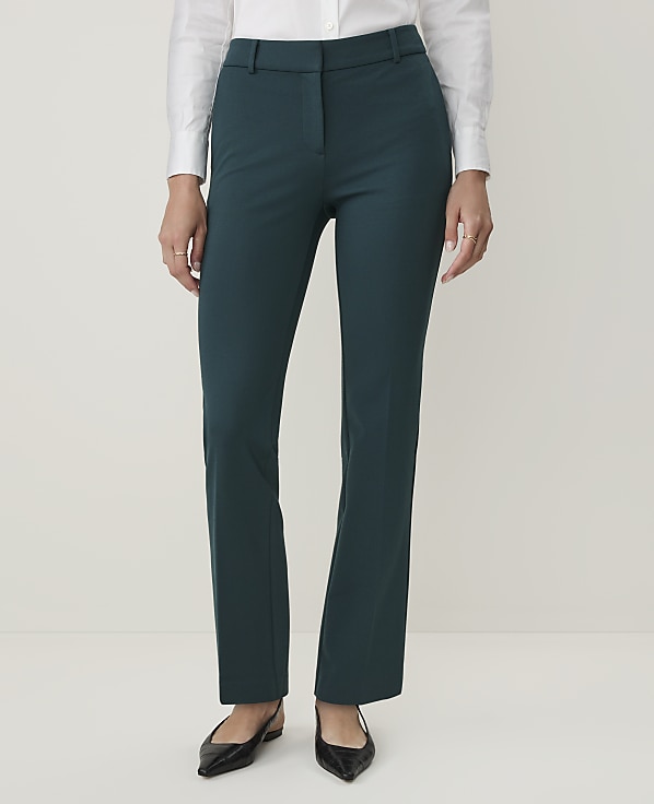A person in a white shirt and teal pants stands against a plain white background.