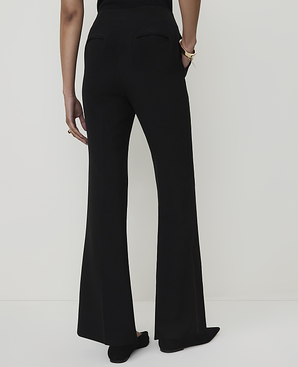 A person wearing black flared pants stands against a plain white background.