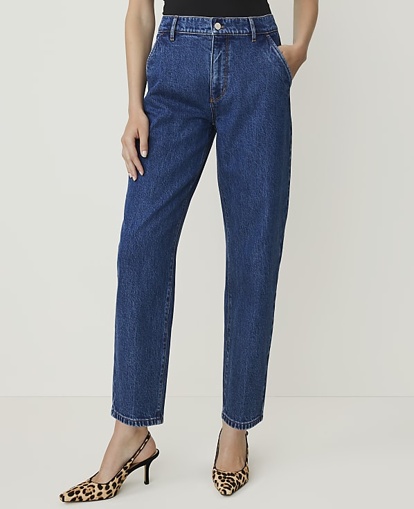 A person stands in dark blue denim jeans and leopard print heels against a plain white background.