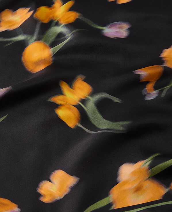 Orange and purple flowers with green stems are scattered across a black, silky background.