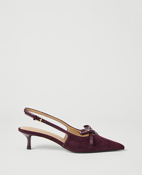 A deep purple suede slingback heel with a small bow detail rests on a plain white background.