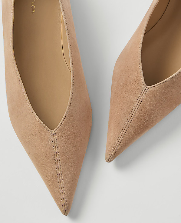 Two pointed, nude suede heels are arranged on a white background.