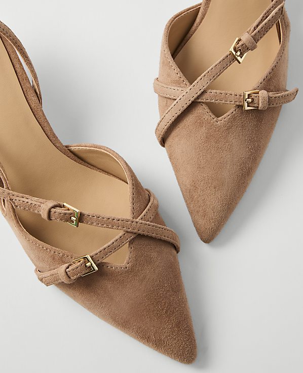Two tan suede pointed-toe heels with delicate straps and gold buckles are arranged on a plain white background.