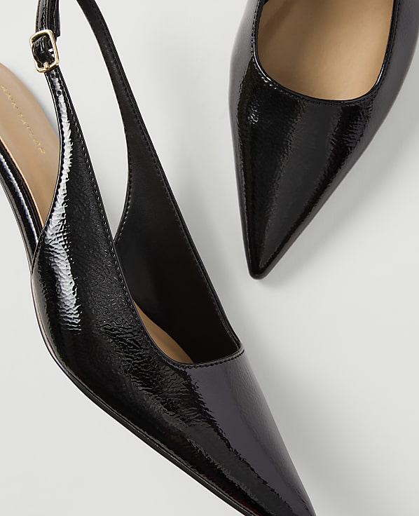 Two glossy black patent leather slingback heels with pointed toes are arranged on a plain white background.