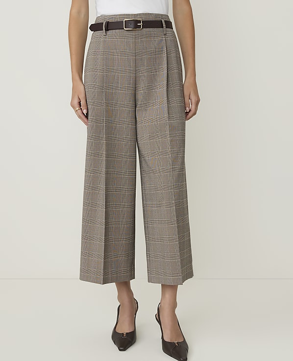 A person stands in the foreground wearing plaid culottes and heels against a plain white background.