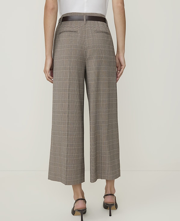 A person wearing plaid culottes and heels stands against a plain white background.