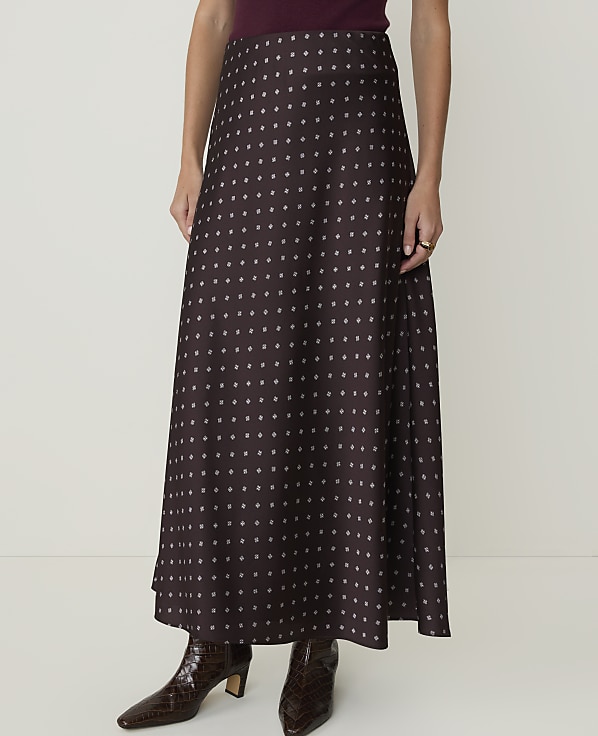 A woman in a patterned maxi skirt and croc-embossed boots stands against a plain white background.