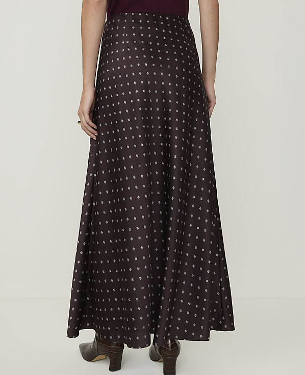 A person wearing a long, patterned skirt and boots stands against a plain white background.