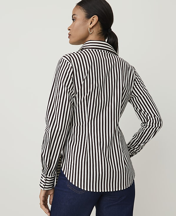 A woman in a black and white striped shirt stands against a plain white background.