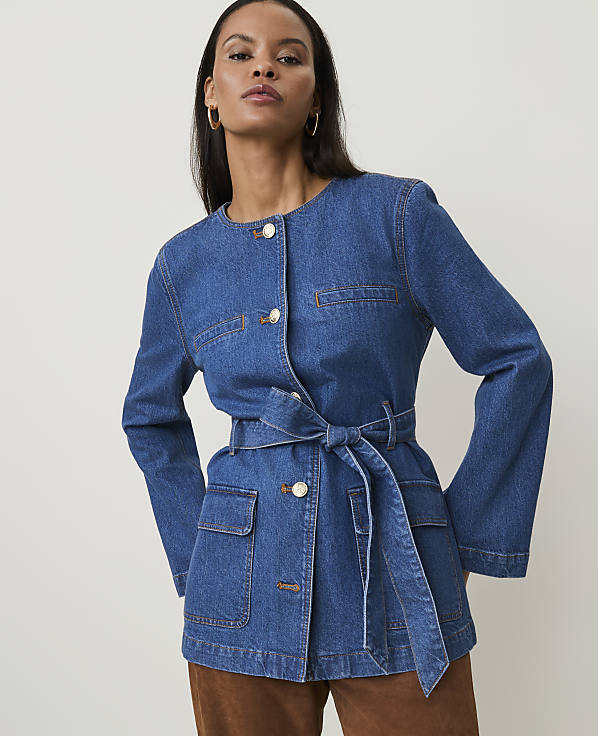 A woman in a denim jacket stands against a plain white background.