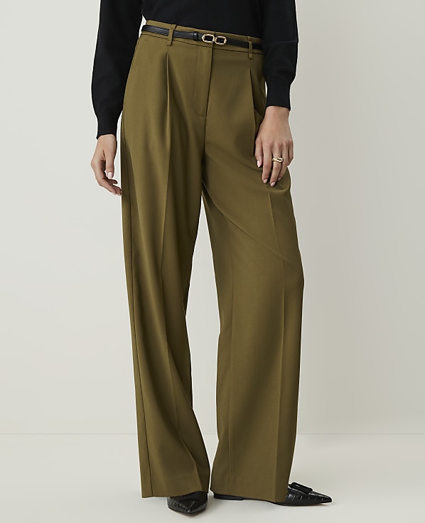 A person in olive green wide-leg pants and a black top stands against a plain white background.