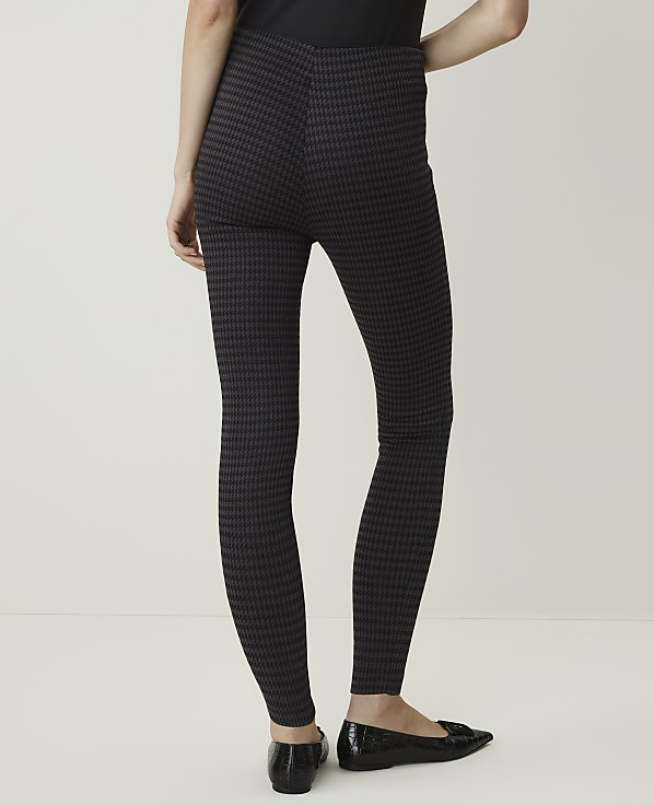 A person wearing patterned leggings and black flats stands against a plain, light-colored background.