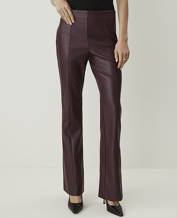 A person in burgundy faux leather pants and black heels stands against a plain white background.