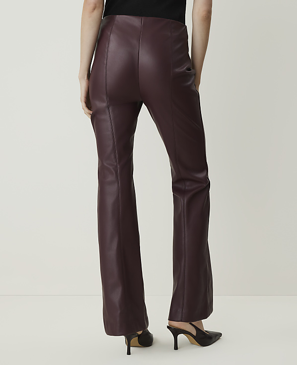 A person wearing burgundy faux leather flare pants and black heels stands against a plain white background.