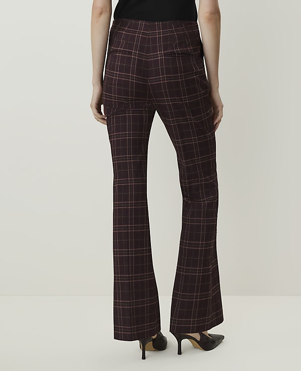 A person wearing flared plaid pants and heels stands against a plain white background.