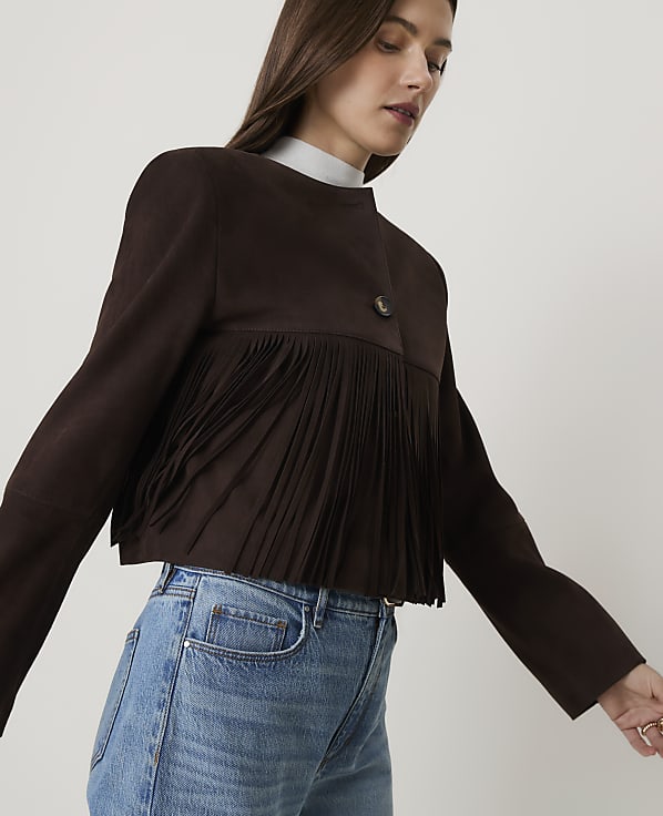 Brown fabric with fringe and buttons in the foreground is set against a blurred background.