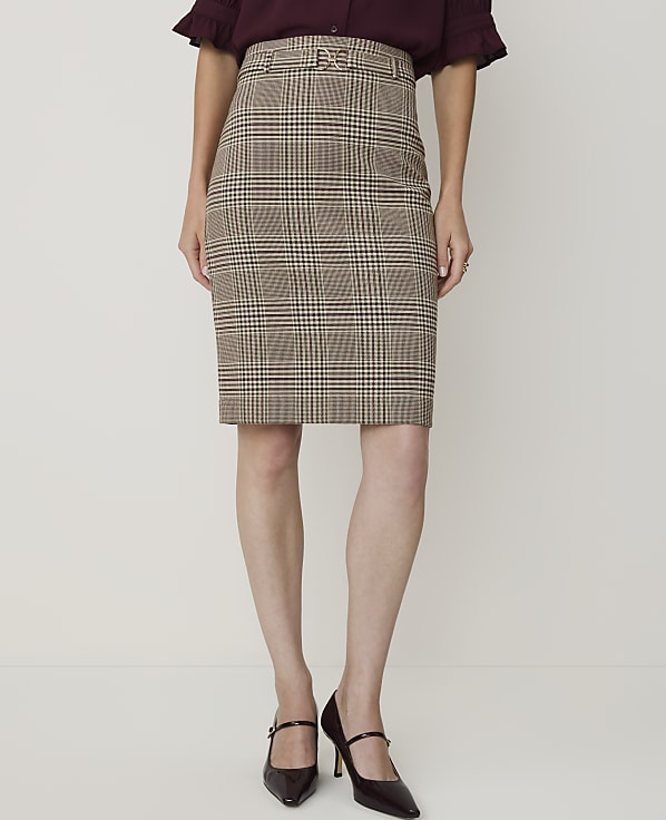 A woman models a brown plaid pencil skirt and dark heels against a plain white background.