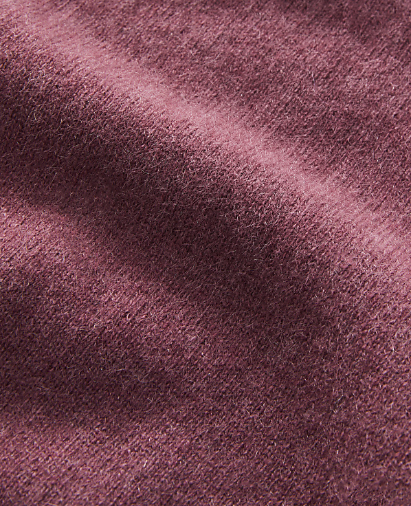 A close-up of a textured, rose-colored fabric with soft folds fills the frame, with no discernible background.