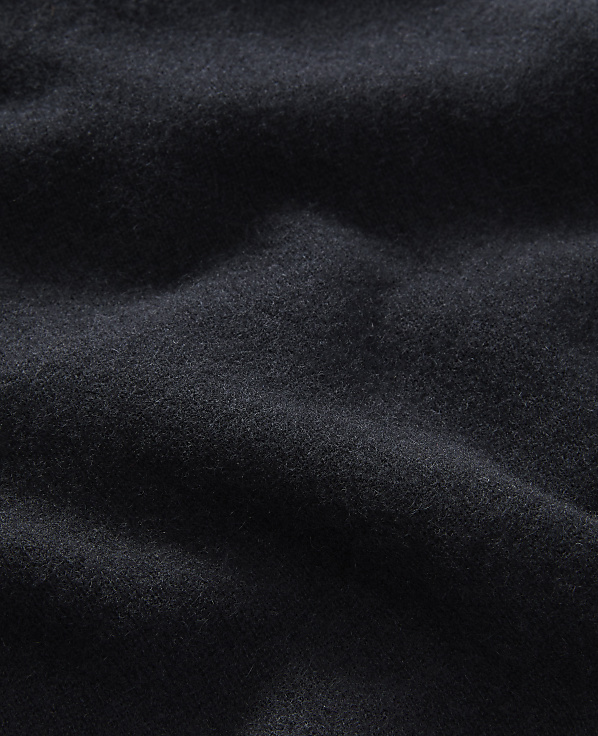 A dark, textured fabric with soft folds fills the frame, creating a sense of depth and shadow.