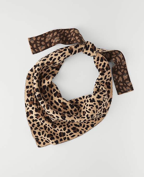 A leopard-print bandana with brown accents is laid flat against a plain white background.