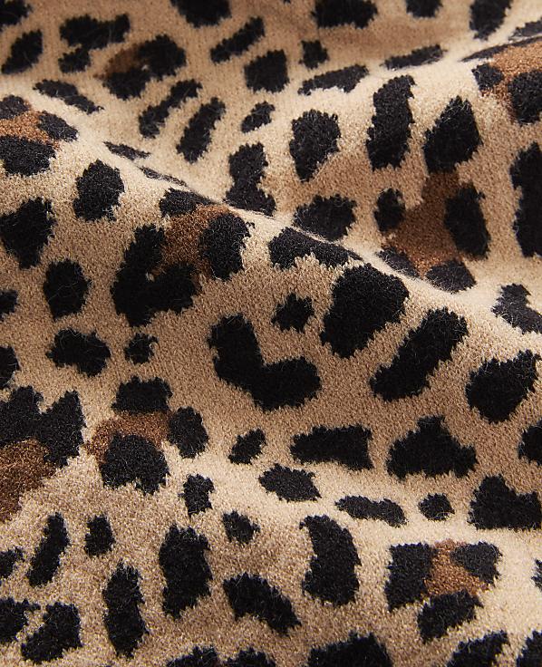 A close-up view of a tan fabric with a black and brown leopard print pattern fills the frame, with soft folds and textures visible throughout.