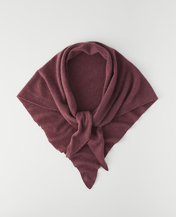A maroon knitted scarf is laid flat on a white background.