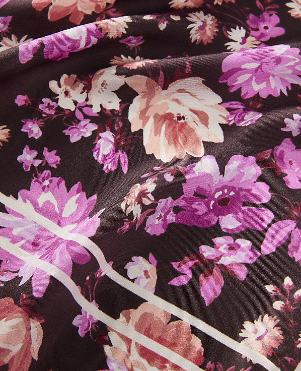 A dark background is filled with a vibrant floral pattern of pink and peach flowers, with white stripes cutting across the foreground.