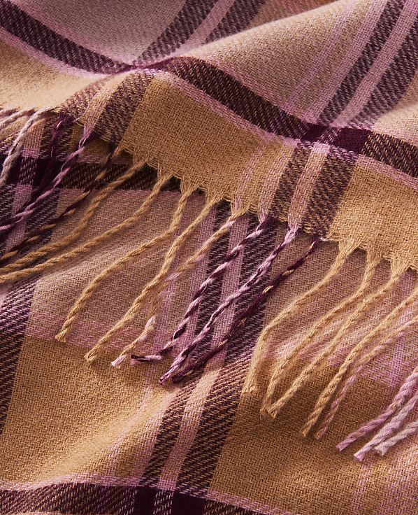 A close-up of a fringed, plaid scarf in shades of pink and tan fills the frame.