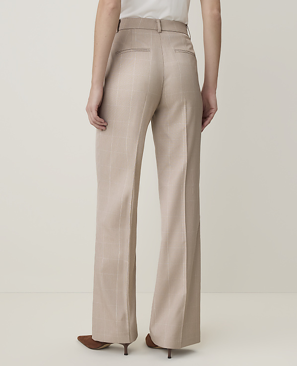 A person wearing beige wide-leg trousers stands against a plain, light-colored background.