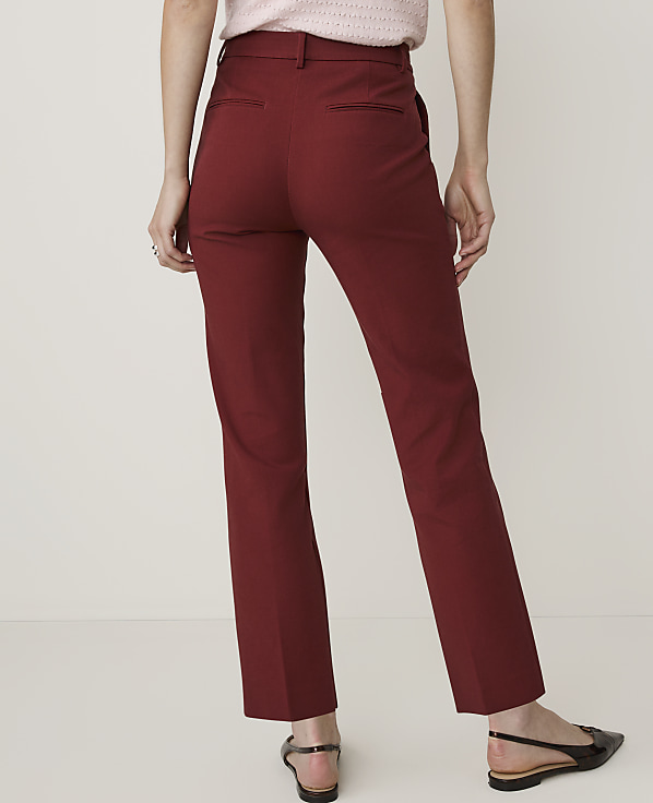A person wearing maroon ankle-length pants and black flats stands against a plain white background.