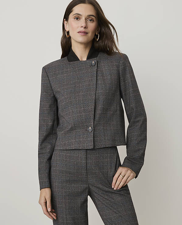A woman in a plaid suit stands against a plain, light gray background.