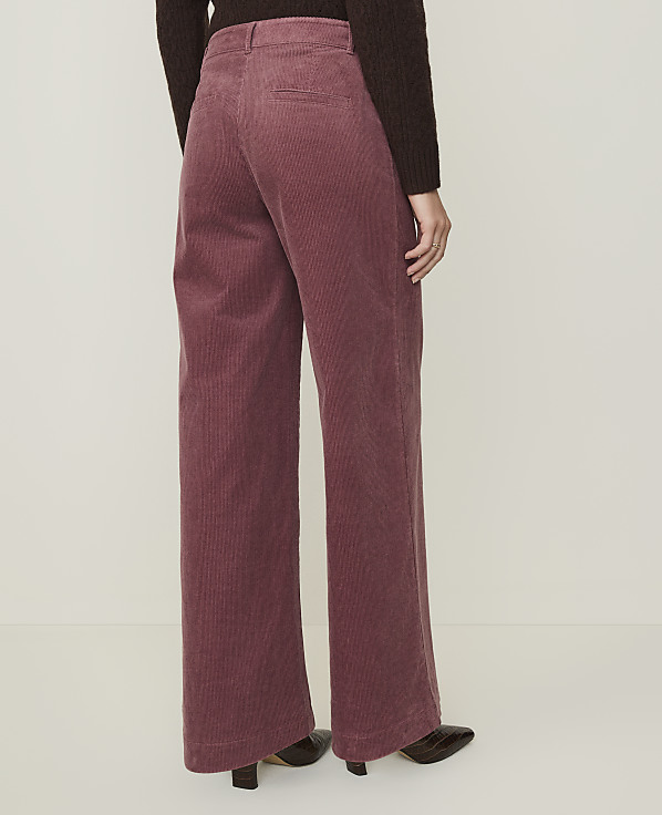 A person wearing rose-colored corduroy pants and dark shoes stands against a plain, light-colored background.